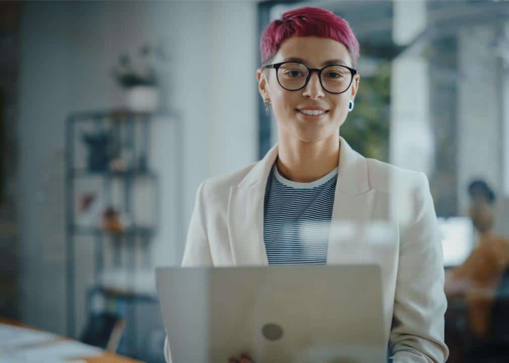 History of LGBTQ+ inclusion in the American workforce image 1 -- pink-haired woman working at a computer